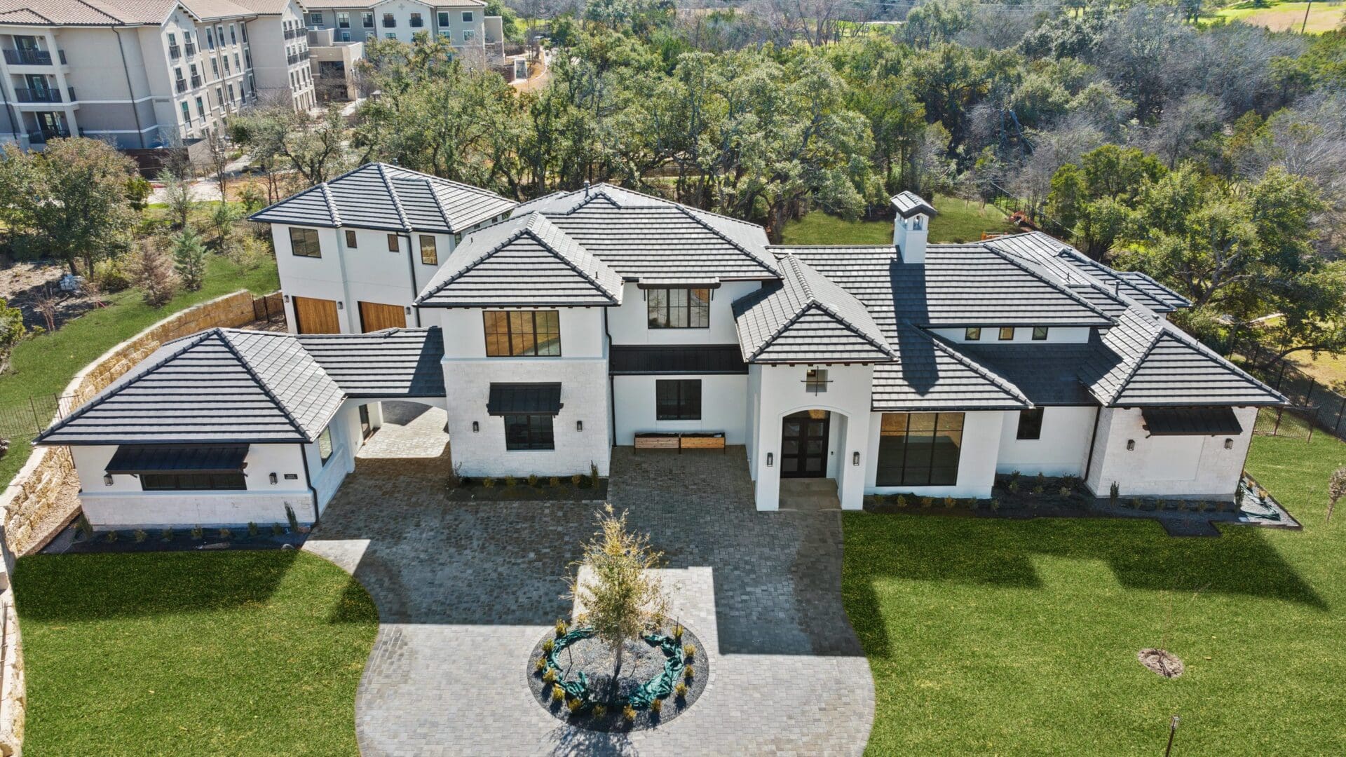 A modern white two-story house with a landscaped front yard and circular driveway.