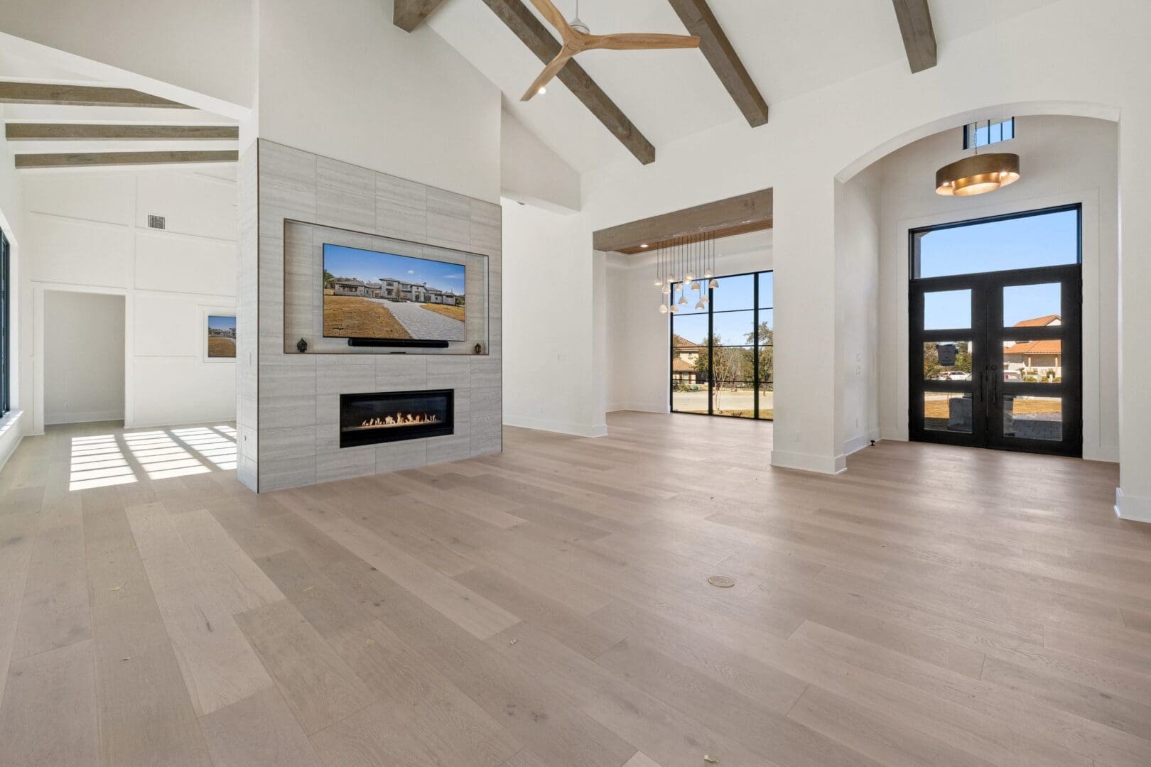 Modern living room with light wood flooring and large windows.
