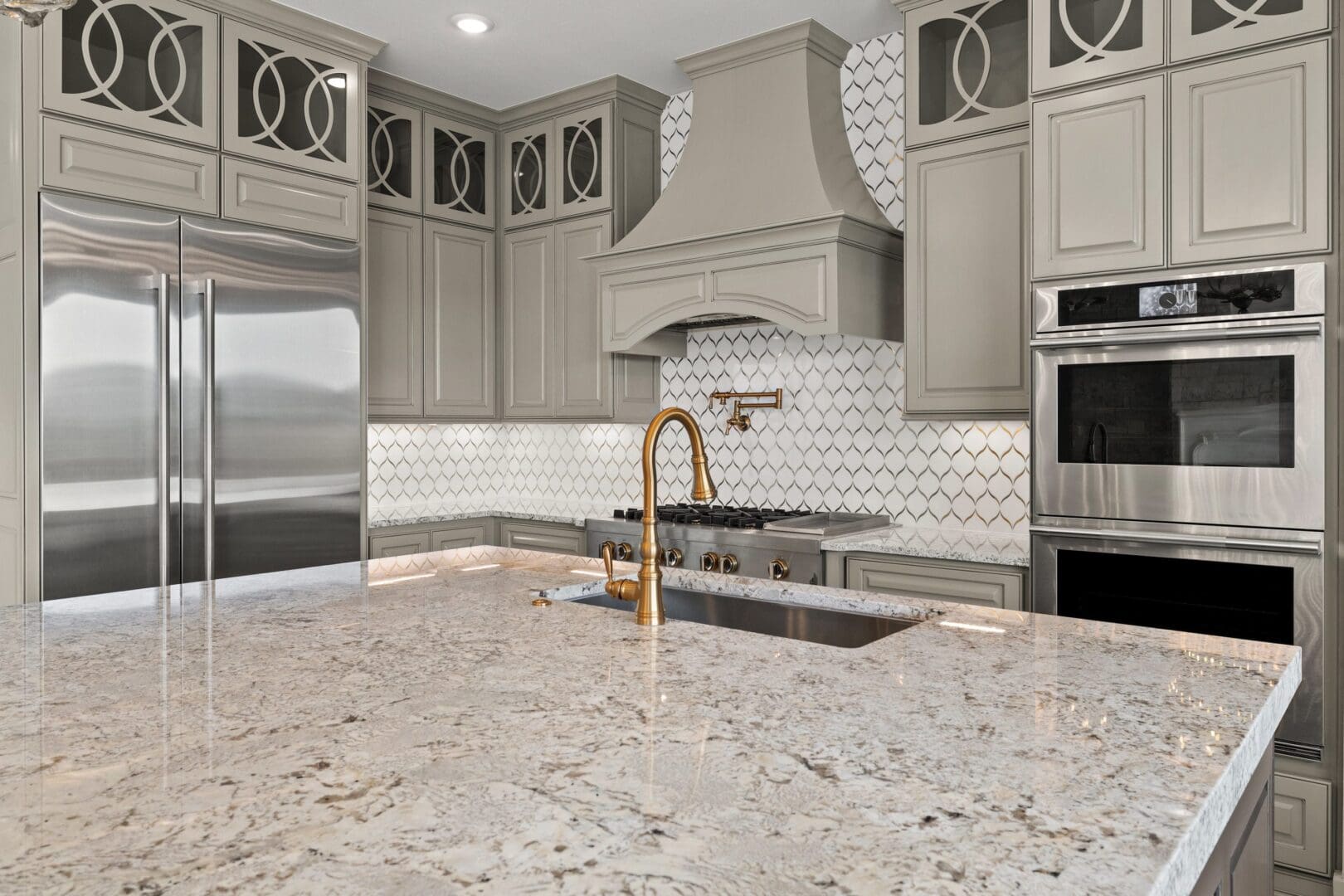 Modern kitchen with beige cabinets, stainless steel appliances, and a granite countertop island.