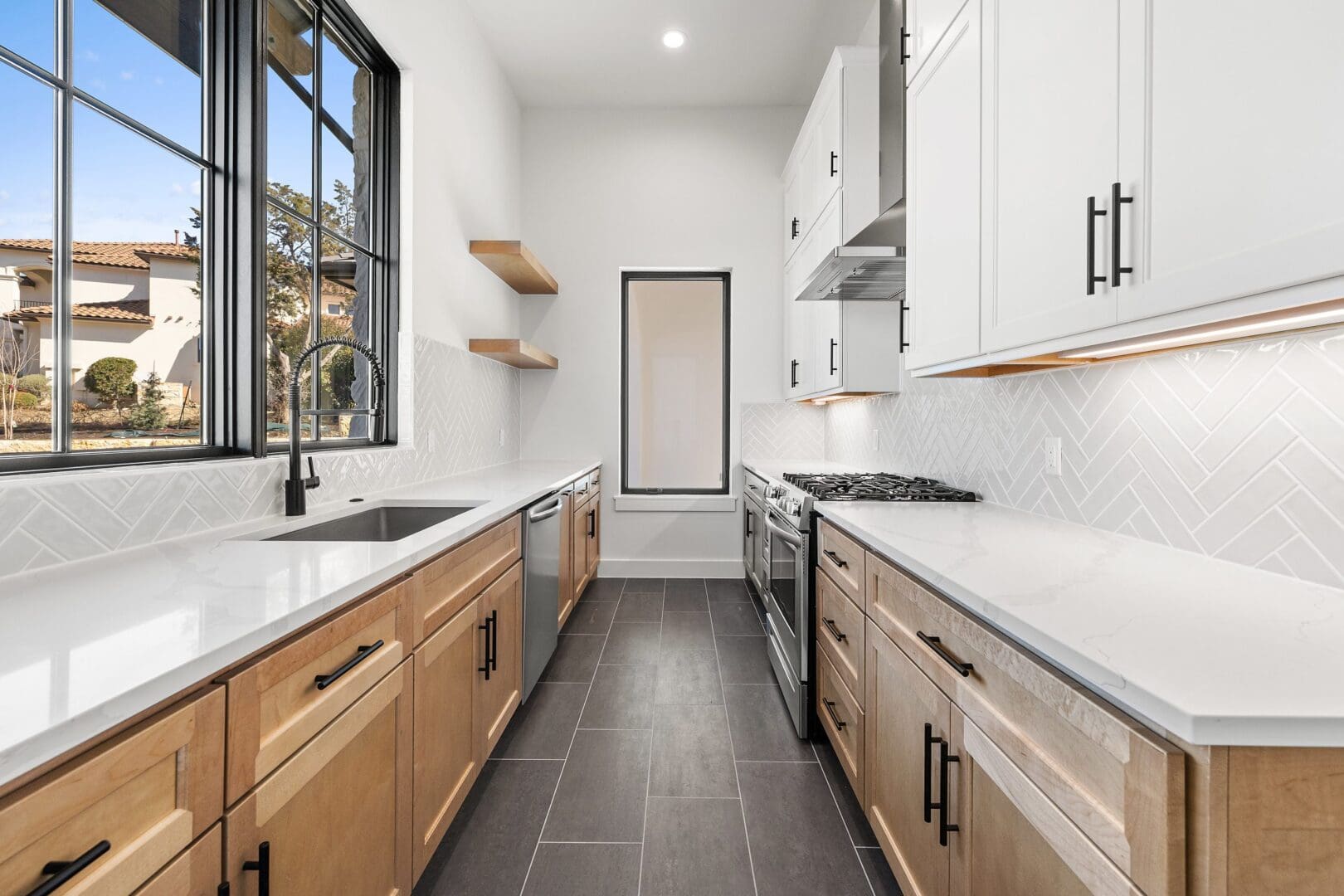 Bright modern kitchen with wood and white cabinetry and large window.