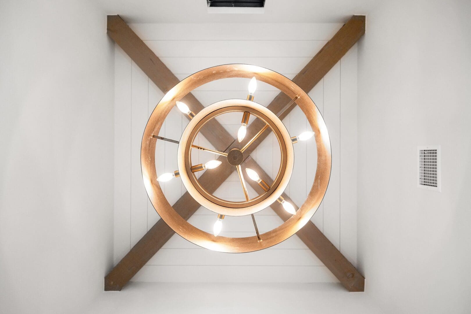 Modern circular chandelier with wooden accents on a white ceiling.