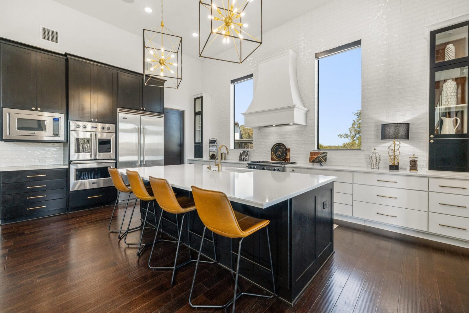 Modern kitchen with black island and yellow bar stools.