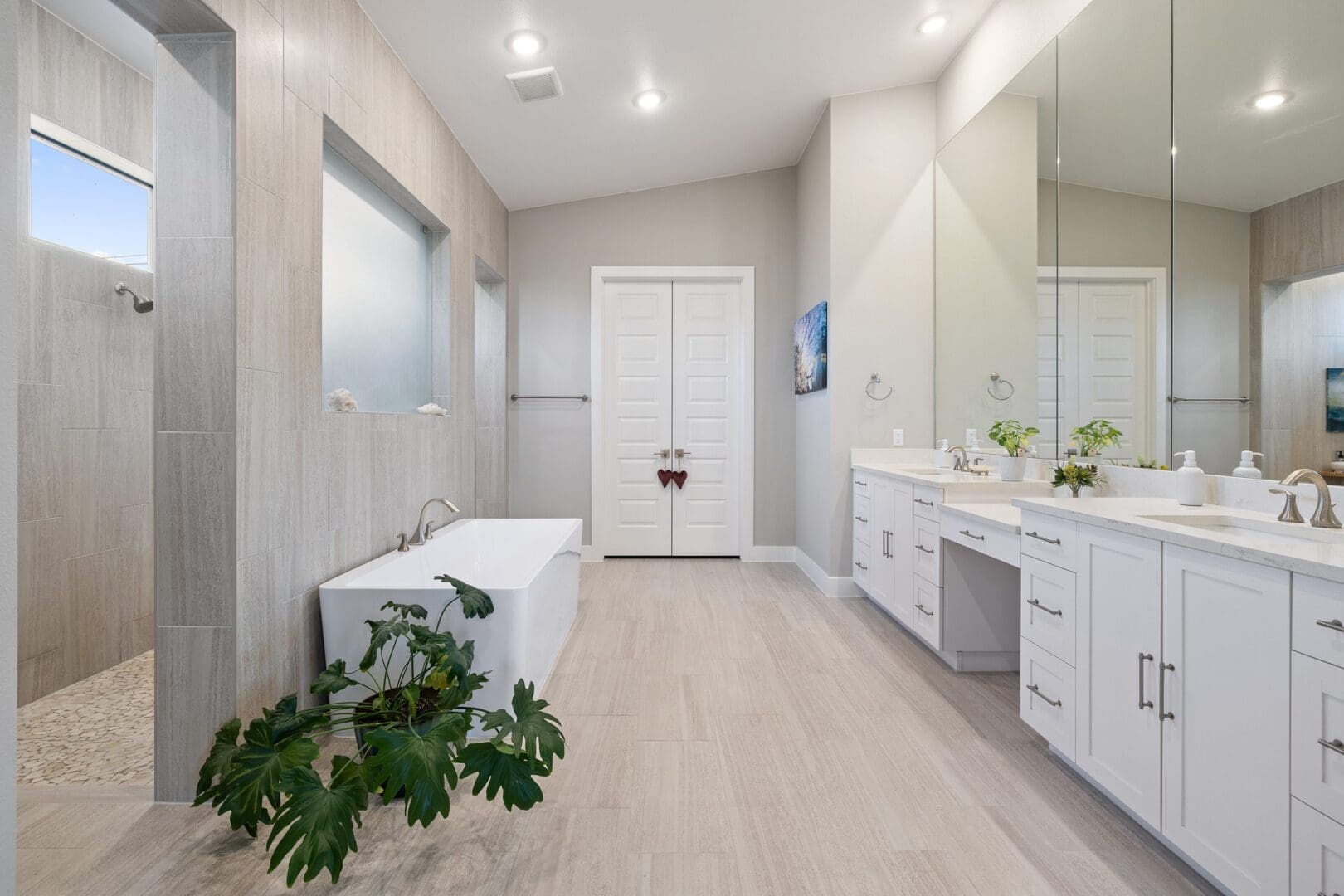 Bright modern bathroom with white fixtures and green plants.