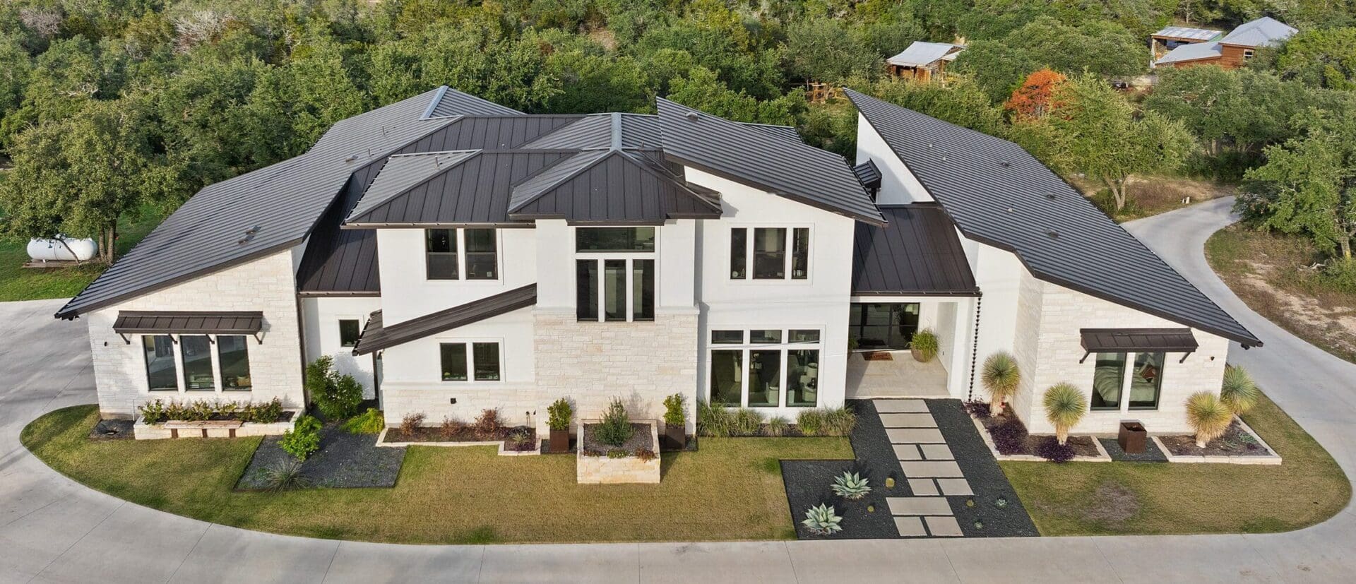 Modern white two-story house with dark roofing and a well-kept lawn.