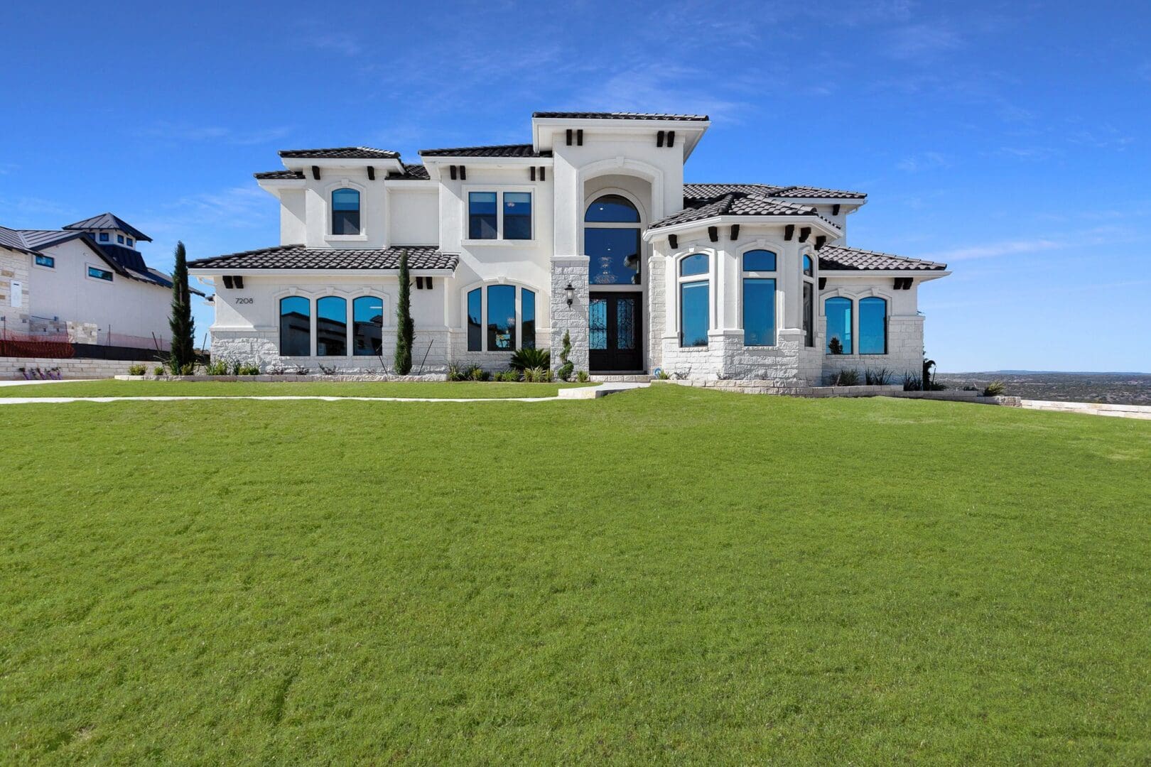 A large modern mansion with blue-tinted windows under a clear sky.