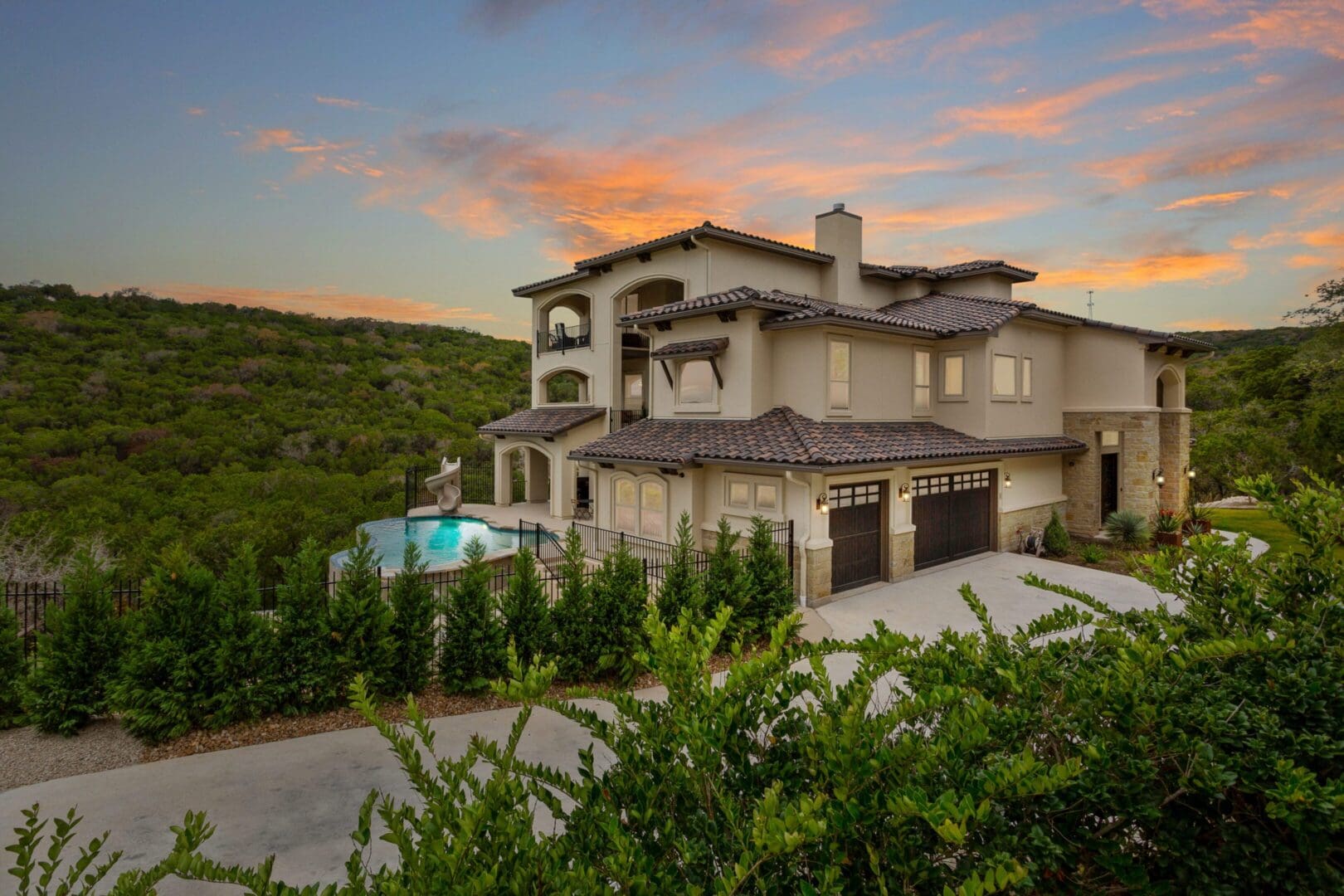Luxurious villa with a pool at sunset surrounded by greenery.