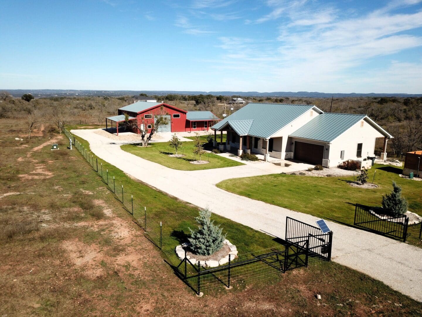 Aerial view of a farmhouse with multiple buildings and open land.