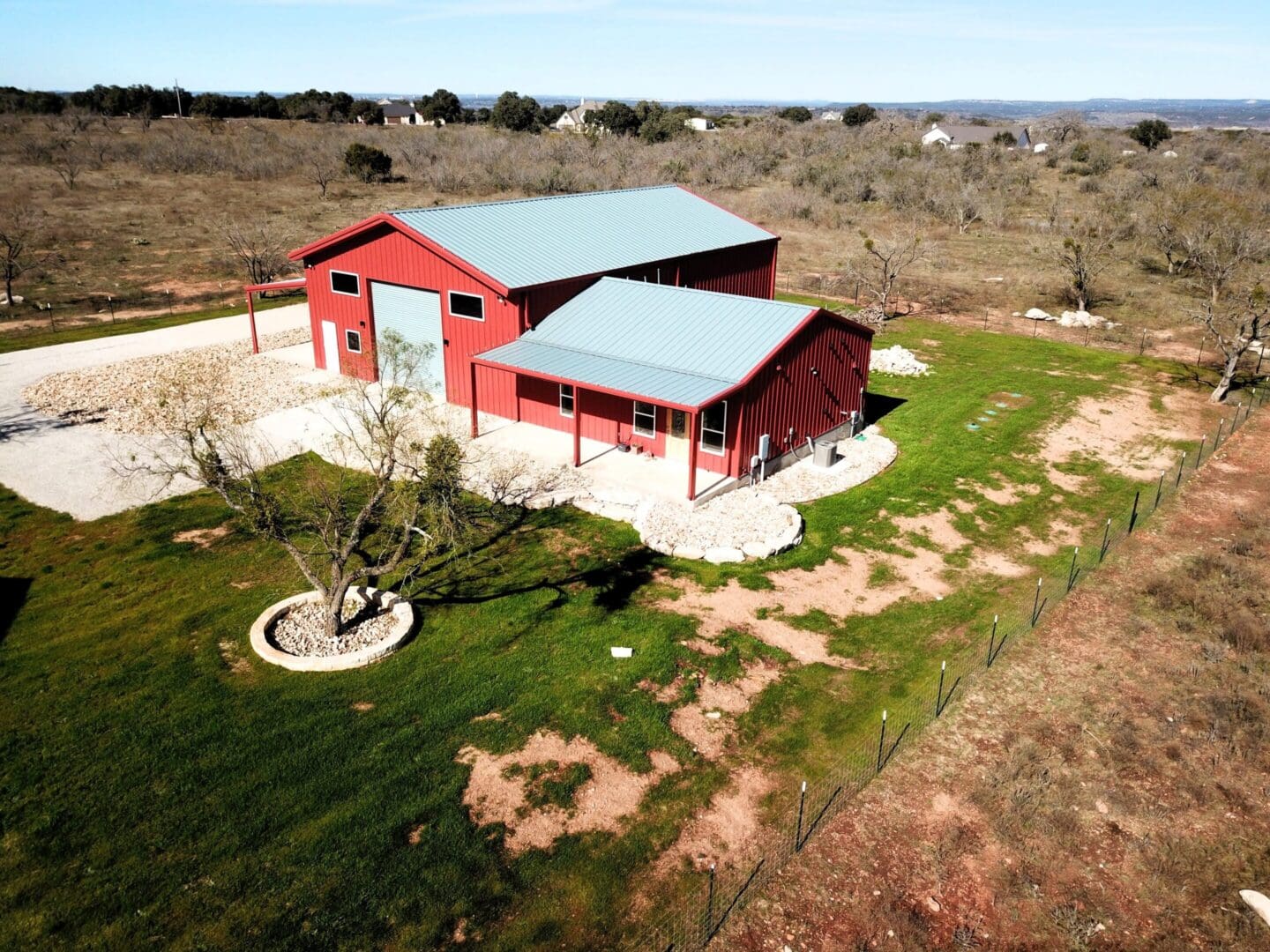 A red barn with a gray roof in a rural area under clear skies.