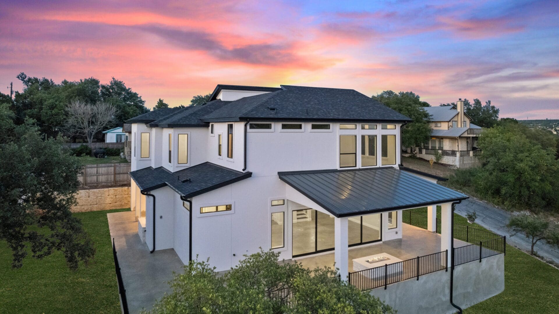 Modern two-story house with large windows at sunset.