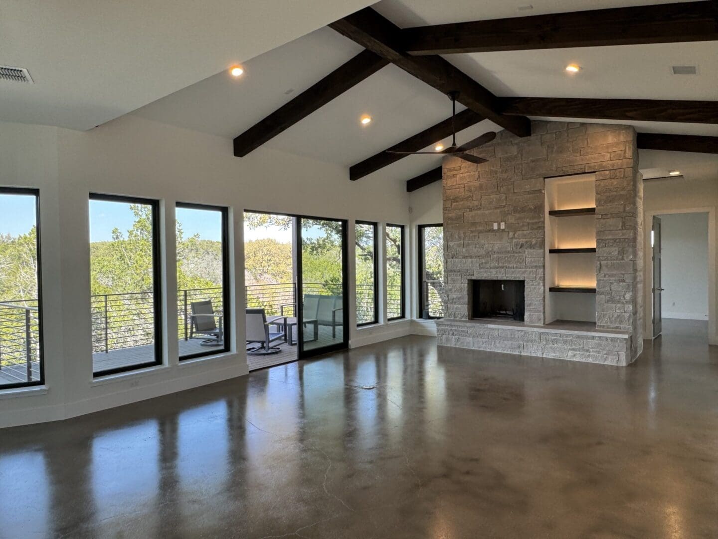 Spacious modern room with large windows and stone fireplace.