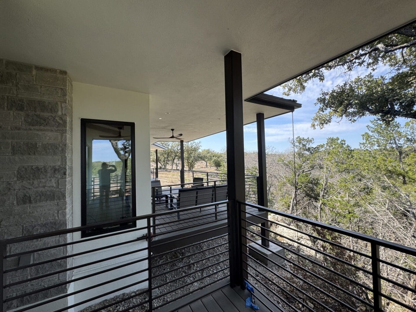 Modern balcony with glass door and scenic forest views.