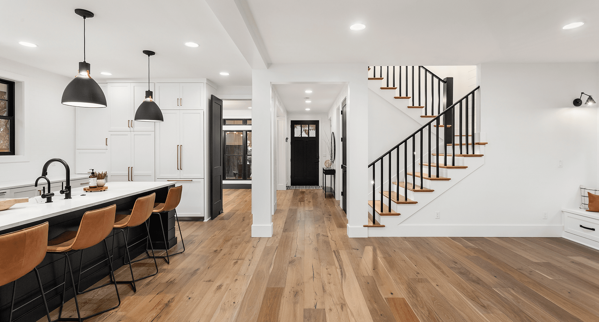 Modern open-concept home interior with wooden floors and staircase.
