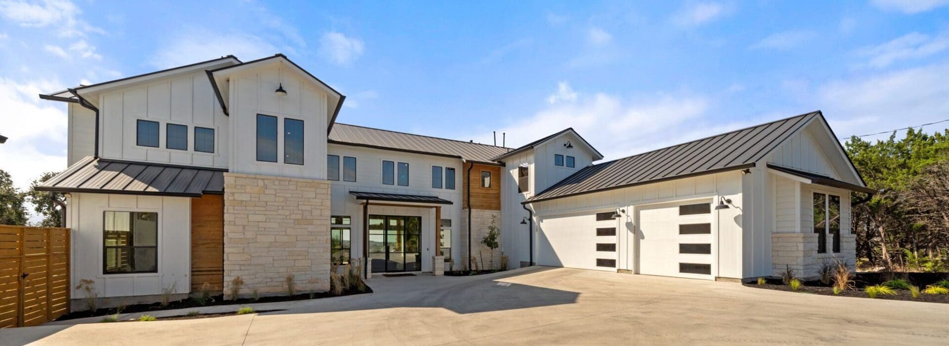 Modern two-story house with stone and wood accents under a clear blue sky.
