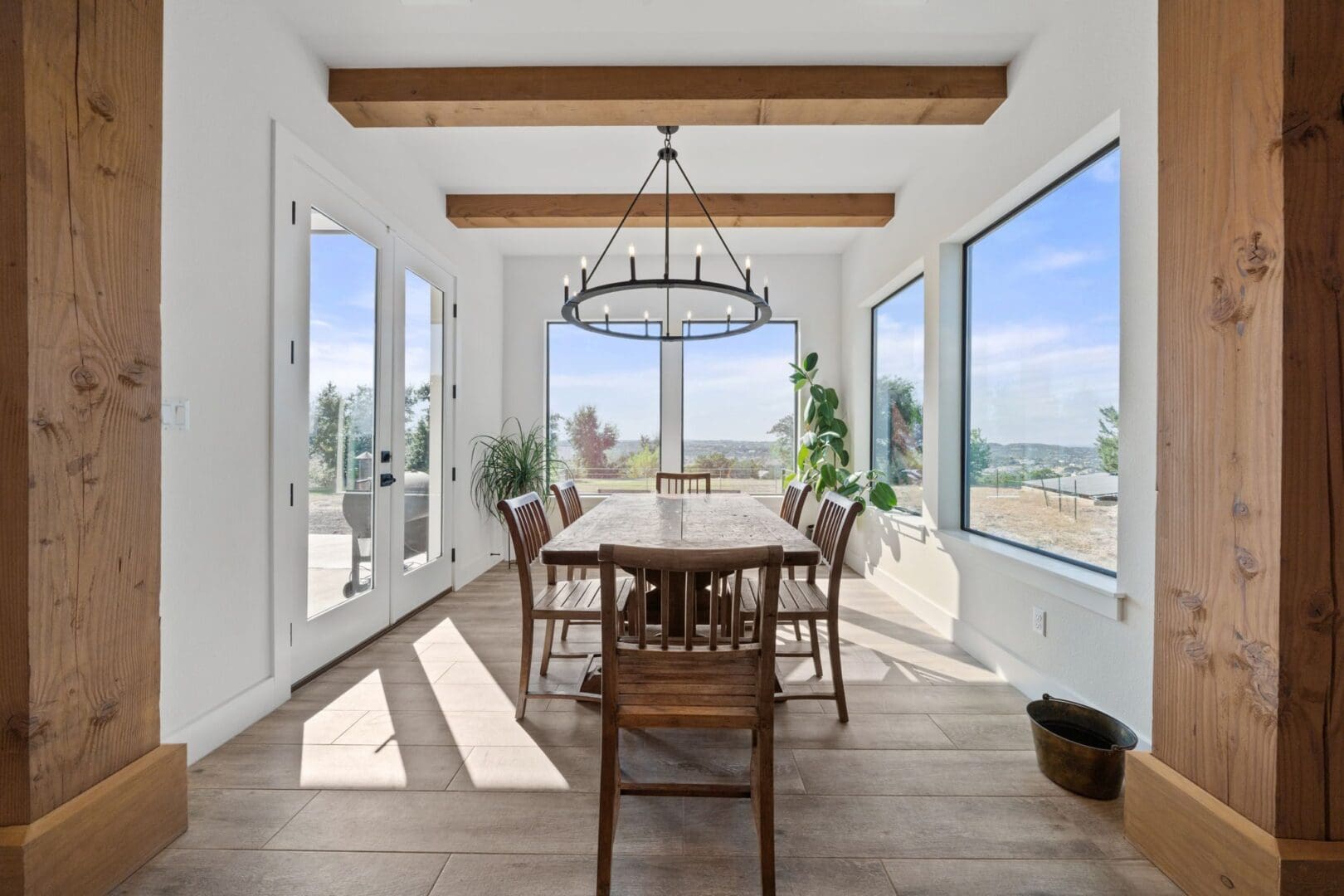 Bright dining room with wooden table and large windows offering a scenic view.